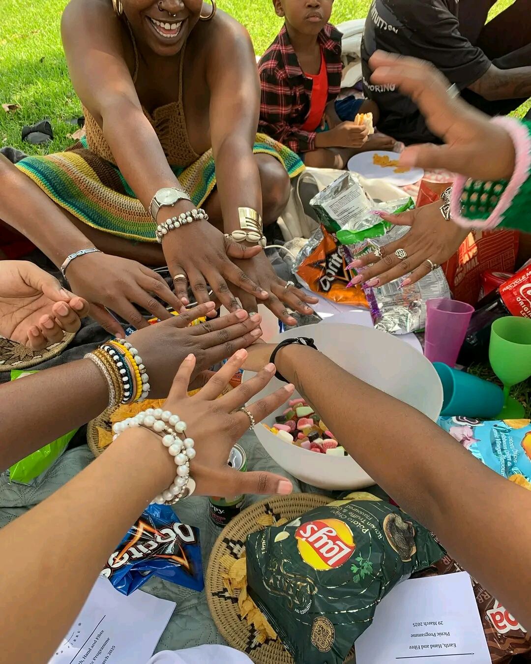 Hands reaching into the middle of a picnic blanket at a crochet picnic